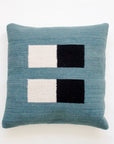 The Pillow 04: Blue + Black by Ania Brzeski is a square, handwoven pillow in teal, featuring modern cream and black rectangles arranged in two horizontal rows on a plain white background.