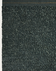 Close-up of the Palus Rug - Fir by Armadillo&Co, showing its textured, dark surface with a rough, marled wool-like appearance and a straight top edge.