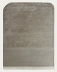 The rectangular Etoile Rug - Dusk by Armadillo&Co is beige Tibetan-knotted wool with rounded top corners, a subtle darker band near the bottom, and short white fringe on the edge, displayed against a plain background.