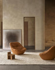 Minimalist living space with neutral-toned walls, two brown leather lounge chairs, a small wooden side table, the Armadillo&Co Nala Rug in Natural & Slate, large abstract art, stairs in the background—crafted sustainably.