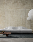 Minimalist living room with a sculptural white sofa, large paper lanterns, a low wooden coffee table, a small vase with twigs, and textured beige walls for a calm, modern atmosphere. The space is anchored by the Sherpa Rug – Kelp from Armadillo&Co, its hand-woven wool design adding warmth and artisanal character to the serene setting.
