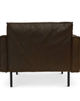 The Attendant Lounge Chair by Wooden Stories features dark brown leather, French seams, square arms, feather-padded panels, and slim black metal legs. Shown from the back against a white background.