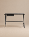 A minimalist black oak Author Desk from Wooden Stories, part of the Danish collection, featuring a small central drawer and set against a plain beige background.