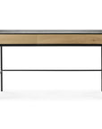 The Ethnicraft Blackbird Desk features a black metal frame, two light European oak drawers, and a dark wood top, shown against a white background.