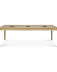 The Bok Cowork Desk - Oak by Ethnicraft features a rectangular European oak tabletop with four legs and three rectangular cutouts for wire management, shown against a plain white background.