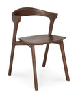 The Bok Dining Chair by Ethnicraft features minimalist Scandinavian style with a curved backrest, smooth edges, and angled legs. Crafted from FSC-certified brown teak, this modern wooden chair highlights a dark wood finish.