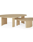 Two Ethnicraft Boomerang Coffee Tables in oak feature fluted, curved legs and rounded tops. Their light natural wood finish and overlapping design create a striking minimalist look inspired by classic European style.
