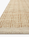 A close-up of the Loloi Cornwall Rug in Ivory / Natural, featuring a textured jute and wool pattern, is shown angled on a white background.