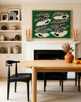 A modern dining room features the Wooden Stories Cove Dining Table in light oak, black chairs, a vase with dried flowers and oranges, pottery on shelves, and bold bird art above a white fireplace set against a green background.