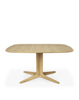 The Ethnicraft Corto Dining Table - Oak Square features a light solid oak rounded square tabletop and a central pedestal base with four legs, showcased against a plain white background.