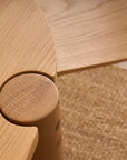 Close-up of Wooden Stories’ Cove Dining Table - Light Oak, set on a textured woven rug. The table’s rounded edges and circular joint detail, inspired by Sydney Harbor, add subtle elegance to the dining space.