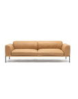 The Department Sofa | Leather by Wooden Stories is a modern, minimalist tan leather sofa with plush cushions, slim black metal legs, and a solid wood base inspired by Danish collections, shown on a plain white background.