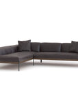 The Wooden Stories Department Modular Sofa | Leather • M6 is a modern L-shaped sectional in dark gray leather with three matching cushions, slender black metal legs, and a minimalist Danish-inspired design set against a plain white background.