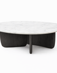 The Eden Coffee Table by Wooden Stories features a round Carrara marble top and a black solid American oak base with curved, intersecting panels—a modern piece embodying Scandinavian simplicity.