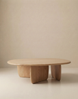 The Eden Coffee Table by Wooden Stories features a modern, oval solid wood design with three thick curved legs, highlighting Scandinavian simplicity against a neutral beige background.