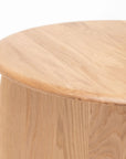 Close-up of the Eden Side Table by Wooden Stories, a round solid wood piece made from American oak with a smooth surface and natural grain, shown against a plain white background.