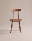 A minimalist Figura Dining Chair | Latte Oak by Wooden Stories, featuring a rounded seat and backrest, four angled legs, and a smooth finish, is displayed against a neutral beige background.