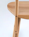 Close-up of the Figura Dining Chair | Light Oak by Wooden Stories, highlighting the smooth curved seat, seamless leg joint, and natural wood grain. Minimalist heritage woodworking design stands out against a plain light background.