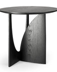 The Geometric Side Table - Black Oak by Ethnicraft features a round top and intersecting sculptural base with curved and straight edges, shown here against a white background.
