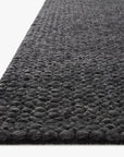 Close-up of the Hendrick Rug - Charcoal by Loloi, showing the corners dark gray, hand-woven wool with a looped, pebble-like pattern against a white background.