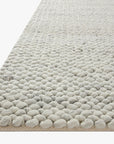 Close-up of the Hendrick Rug - Ivory by Loloi, showcasing its light grey, hand-woven wool construction with a chunky, pebble-like pattern and soft, plush texture.