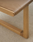 Close-up of the Hover Bench | Leather Seat by Wooden Stories, featuring a solid oak frame with smooth edges and brown leather seat, set on a light textured carpet. Its modern Scandinavian design combines minimalism and elegance.