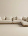 The Islet Modular Sofa | Fabric • M2 by Wooden Stories is a modern L-shaped beige sectional with wooden legs and multiple back cushions, shown against a plain beige background.