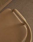 A top-down view of the Wooden Stories Inlay Counter Stool with a leather seat, shown on a textured brown carpet beside a wooden desk.