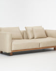 The Islet Sofa | Leather by Wooden Stories is a modern beige sofa with durable leather upholstery, wooden legs, two large seat cushions, and three matching back cushions, shown against a plain white background.
