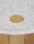 A close-up of the Wooden Stories Pivot Side Table | Light Oak shows its white marble top with a circular wooden inlay and partially visible solid wood legs, reflecting Danish-inspired design.