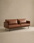 Introducing the Cherry Sofa | Leather by Wooden Stories—a modern brown leather 3-seater featuring two spacious seat and back cushions, sleek slim armrests, and sturdy black metal legs. Shown against a plain beige background, this sofa is perfect for bringing exceptional comfort and contemporary style to any modern living space.
