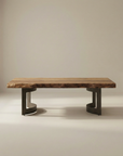 The Moes Leviathan Live Edge Coffee Table features a thick acacia wood slab top with natural edges and two dark, curved geometric metal legs, set against a plain beige background.