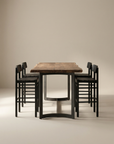 The Moes Leviathan Live Edge Counter Table features a natural slab top and black metal legs, paired with six matching black chairs, all set against a plain beige background.