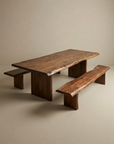 A wooden dining table with a natural, live-edge design is paired with two SOBU Leviathan Live Edge Benches - Wood Legs. The set sits in a simple, neutral-toned room with no other furniture or decorations.