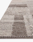A close-up of the Loloi Manfred Rug - Charcoal / Dove highlights its rectangular, hand-knotted patchwork design with textured woven patterns in neutral tones and a soft, plush surface.