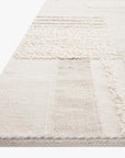 Close-up of the Loloi Manfred Rug in Ivory / Pebble, highlighting its textured woven and tufted patterns in a subtle patchwork design, displayed against a white background.