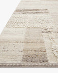 A close-up of the Loloi Manfred Rug - Natural / Stone highlights its hand-knotted patchwork design in cream, beige, and light brown, featuring varied weaves and raised accents for added texture.