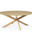 The Mikado Coffee Table Round by Ethnicraft features a smooth solid oak top and three intersecting angled legs for a modern geometric design, capturing the contemporary elegance of the Mikado Collection.