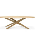 The Ethnicraft Mikado Dining Table Oval - Oak features a modern European oak top and a distinctive intersecting base, shown against a white background.