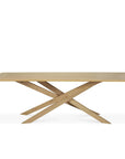 The Ethnicraft Mikado Dining Table Rectangular - Oak features a modern design with a rectangular European oak top and intersecting angled legs, shown against a plain white background.