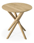 The Mikado Side Table - Oak by Ethnicraft showcases a sleek round solid oak top and three intersecting angled legs, delivering a modern, minimalist look.