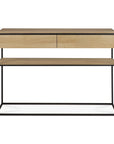 The Monolit Console - Oak by Ethnicraft features a minimalist rectangular design with a black metal frame, solid oak top, two front drawers, and a lower wood shelf.