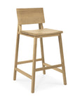 The Ethnicraft N3 Counter Stool - Oak features a simple, minimalist design with a square seat, straight legs, low backrest, and footrests—all crafted from solid oak in a light natural finish.