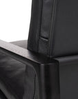 Close-up of the Wooden Stories Troubadour Lounge Chair in black leather with a textured backrest, smooth seat, and dark solid oak armrests, shown against a plain white background.