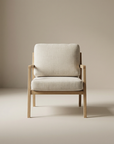 The Nysse Lounge Chair | Fabric by Wooden Stories, featuring solid oak and light beige cushions, sits against a neutral backdrop. Its minimalist design reflects the refined elegance of Scandinavian lounge chair style.