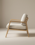The Nysse Lounge Chair | Fabric by Wooden Stories is shown in profile with light beige cushions against a plain background. Crafted from solid oak, it features clean lines and a modern Scandinavian-inspired design.