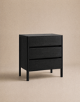 Introducing the Nell Tall Dresser by Wooden Stories—a sleek, modern black wooden dresser with three spacious drawers and premium metal runners for smooth operation, set against a plain beige background. Part of the exclusive Danish Collection, it’s the perfect enhancement to your bedroom storage.