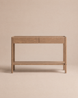 The Nell Console | Latte Oak by Wooden Stories, crafted from solid oak, features two drawers and a lower shelf. Set against a plain beige background, its simple, modern silhouette highlights the natural wood grain in classic Scandinavian design.