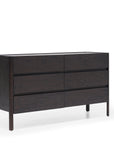 The Nell Wide Dresser by Wooden Stories features six spacious drawers crafted from dark wood, highlighted by clean, modern lines and expert timber joinery. Raised on four slender legs and pictured against a plain white background, this elegant piece from the Danish Collection offers refined and stylish storage for any bedroom.
