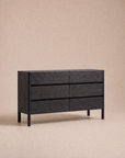 The Nell Wide Dresser by Wooden Stories from the Danish Collection is a modern black wooden dresser with six drawers, showcased on a light beige background. It features minimalist timber joinery, clean lines, and handle-free design, making it an ideal choice for stylish bedroom storage.